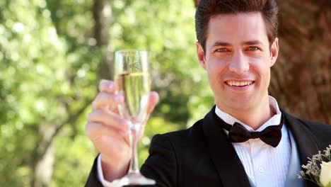 Glückliche-Bräutigam-lächelt-in-die-Kamera-und-Anstoßen-mit-Champagner