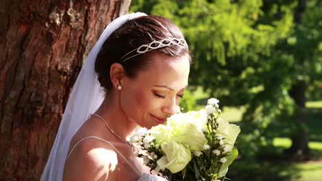 Pretty-bride-holding-a-bouquet-in-the-park
