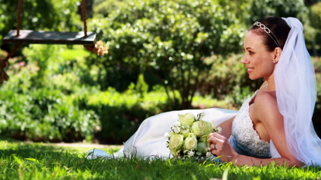 Hübsche-Braut-Kamera-Lächeln-beim-liegen-auf-dem-Rasen