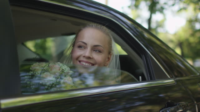Junge-schöne-glückliche-Braut-sitzt-im-Auto-und-Wellen-aus-dem-Fenster.