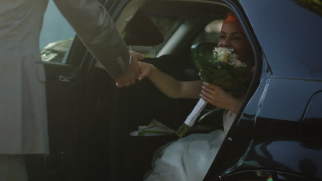 Groom-opens-and-holds-the-car-door-for-the-beautiful-young-bride.