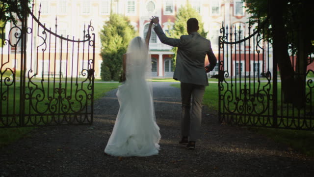 Braut-und-Bräutigam-bewegen-sich-in-Richtung-eines-Herrenhauses-in-einem-Park.