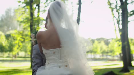 Braut-und-Bräutigam-umarmen-sich-in-einem-sonnigen-Park.