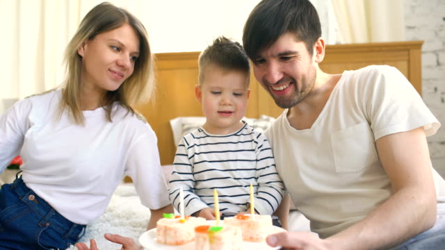 Lächelnde-Familie-feiert-ihren-Sohn-Geburtstag-zusammen,-bevor-Sie-Kerzen-auf-Kuchen-blasen