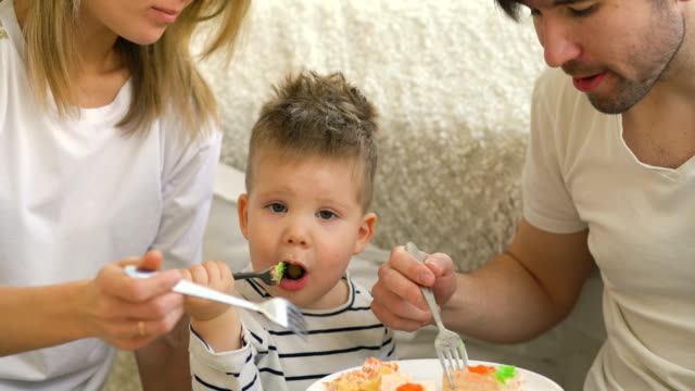 Little-adorable-boy-celebrating-his-birthday-with-father-and-mother-eat-cake-in-bedroom