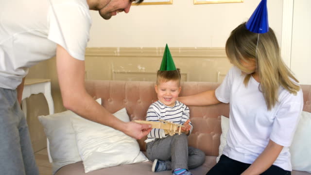 Vater-der-glückliche-Familie-anwesend-Geburtstagsgeschenk-zu-seinem-Sohn-zu-Hause-feiern