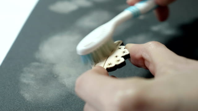 Un-artista-limpia-con-un-cepillo-una-artesanía-de-madera-después-de-moler-en-papel-de-lija