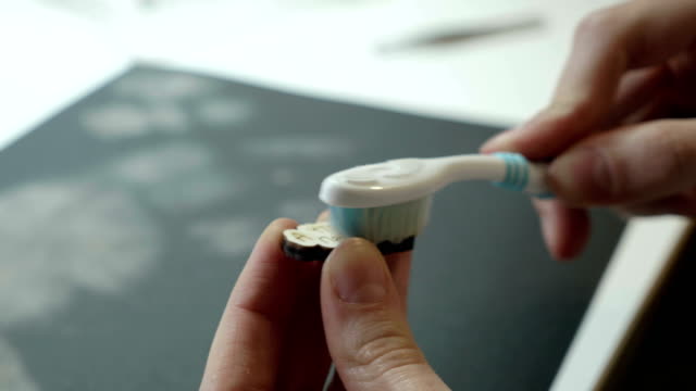 Ein-Künstler-reinigt-mit-Pinsel-ein-hölzernes-Handwerk-nach-dem-Schleifen-auf-Sandpapier