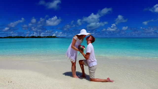 v07387-Maldives-white-sandy-beach-2-people-young-couple-man-woman-proposal-engagement-wedding-marriage-on-sunny-tropical-paradise-island-with-aqua-blue-sky-sea-water-ocean-4k