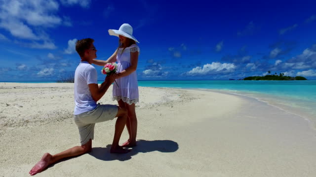 v07385-Maldives-white-sandy-beach-2-people-young-couple-man-woman-proposal-engagement-wedding-marriage-on-sunny-tropical-paradise-island-with-aqua-blue-sky-sea-water-ocean-4k
