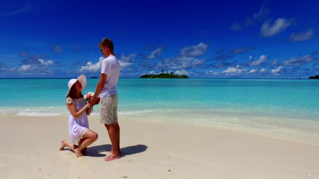 v07390-Maldives-white-sandy-beach-2-people-young-couple-man-woman-proposal-engagement-wedding-marriage-on-sunny-tropical-paradise-island-with-aqua-blue-sky-sea-water-ocean-4k