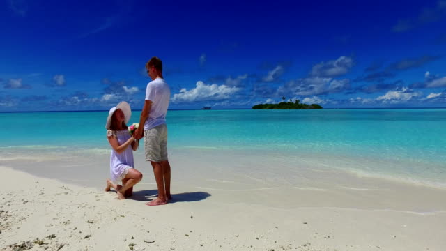v07389-Maldives-white-sandy-beach-2-people-young-couple-man-woman-proposal-engagement-wedding-marriage-on-sunny-tropical-paradise-island-with-aqua-blue-sky-sea-water-ocean-4k