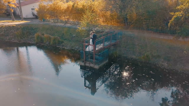 Young-wedding-couple-is-standing-on-a-small-bridge-near-beautiful-lake