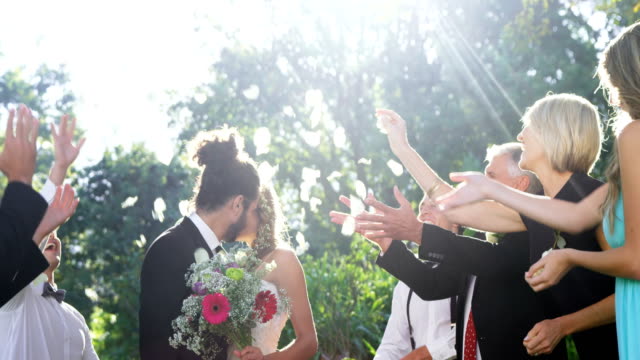 Gäste-werfen-Blütenblätter-während-Braut-und-Bräutigam-küssen-4K-4k