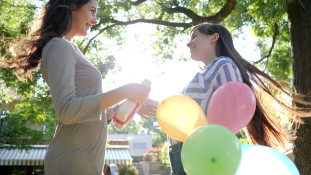 Emotionen-im-sonnigen-Tag,-fröhliche-Frau-mit-bunten-Luftballons-gratuliert-Freund-alles-Gute-zum-Geburtstag-im-park