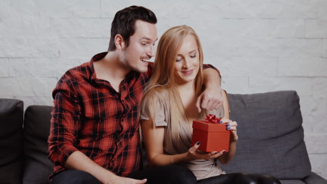 young-man-gives-a-gift-to-a-girl-on-the-couch