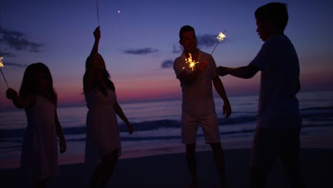 Hispanic-family-celebrating-birthday-with-sparklers-on-beach