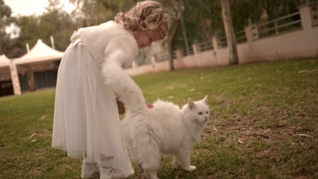 Happy-flower-girl-holding-basket-and-petting-cat-at-wedding