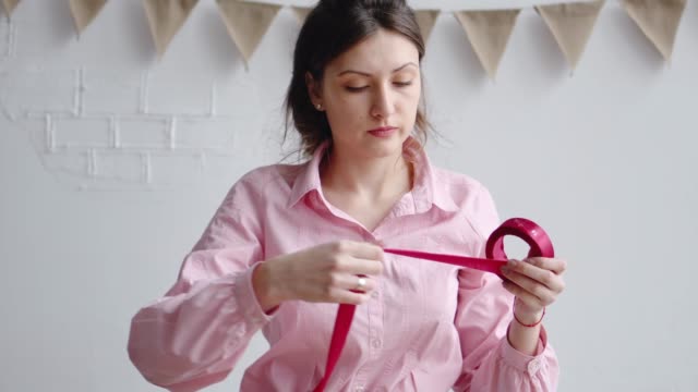 Floreria-de-mujer-profesional-se-desenrolla-la-cinta-roja,-corta-con-tijeras-para-embalar-el-ramo