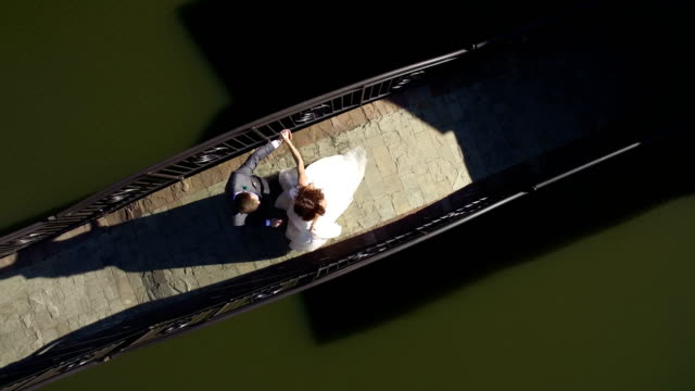 Aerial-view-on-top.-Happy-brides-are-on-a-sunny-day-on-a-bridge-near-the-lake