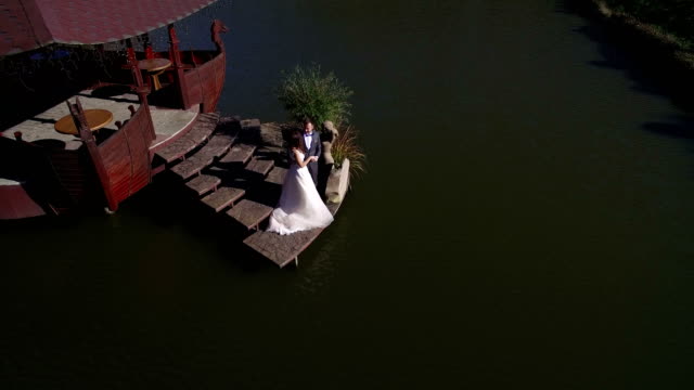 Aerial-view.-Happy-brides-are-on-a-sunny-day-on-a-bridge-near-the-lake