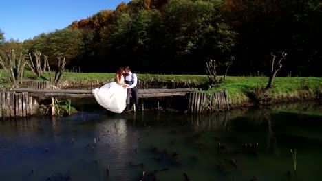 The-brides-sit-near-the-lake-on-a-small-bridge-in-the-park