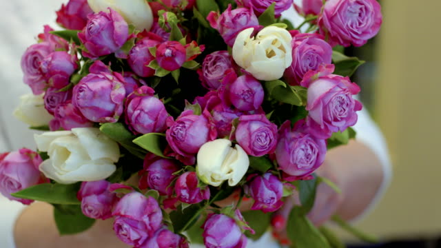 Weibchen-halten-Strauß-Tulpen-und-Rosen