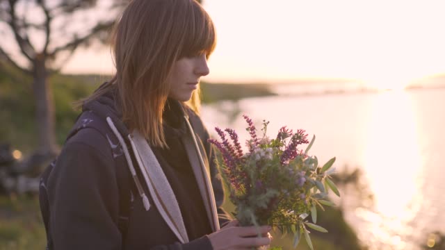 schöne-junge-Frau-mit-einem-Bouquet-von-Wiesenblumen-an-der-Küste-bei-Sonnenuntergang