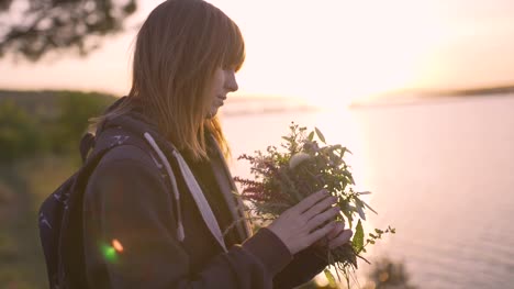 schöne-junge-Frau-mit-einem-Bouquet-von-Wiesenblumen-an-der-Küste-bei-Sonnenuntergang