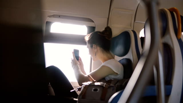 Beautiful-happy-Caucasian-girl-taking-a-smartphone-photo-from-moving-train-window-and-posting-it-to-a-social-network