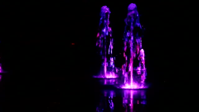 Wasserfontäne-Nacht-Tanz-mit-Lichtern-bunte-Unschärfe-Filmmaterial-Hintergrund-farbig,-Nahaufnahme,-geringe-Schärfentiefe,-59,94-fps