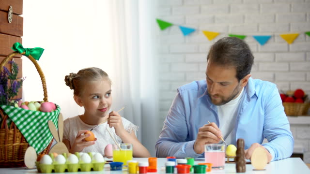Cute-father-and-daughter-preparation-for-Easter-celebration-painting-eggs
