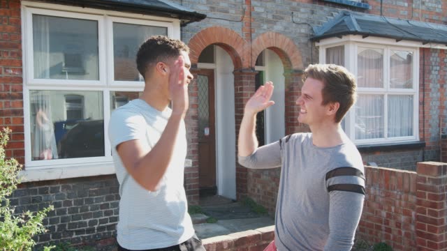 Portrait-Of-Two-Men-Standing-Outside-New-Home--Giving-Each-Other-High-Five