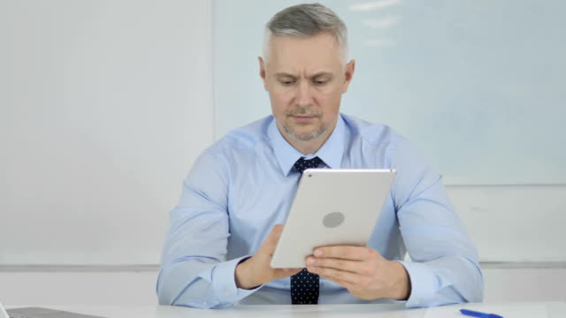 Businessman-Browsing-Internet-on-Tablet-in-Office