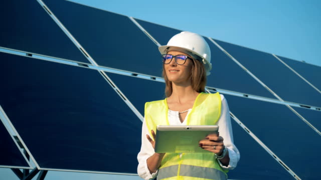 Woman-stands-near-solar-panels-and-smiles,-close-up.