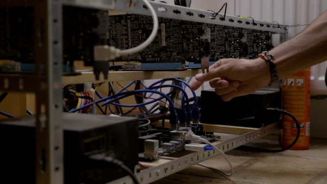 Technician-engineer-man-checking-cable-connections-and-temperature-on-crypto-currency-mining-rig
