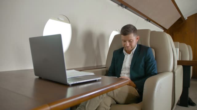 Empresario-hablando-sentado-en-cómodo-sillón-en-cabina-de-avión-privado