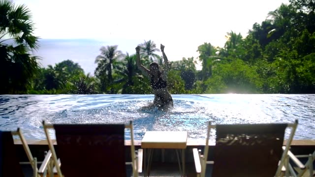 Dos-chicas-jugando-en-la-piscina-al-aire-libre-en-un-día-soleado-en-una-isla-tropical