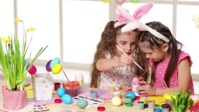 Happy-children-wearing-bunny-ears-painting-eggs-on-Easter-day.
