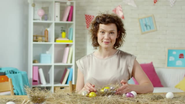 Hermosa-mujer-sonriendo-para-la-cámara-y-preparando-huevos-de-Pascua