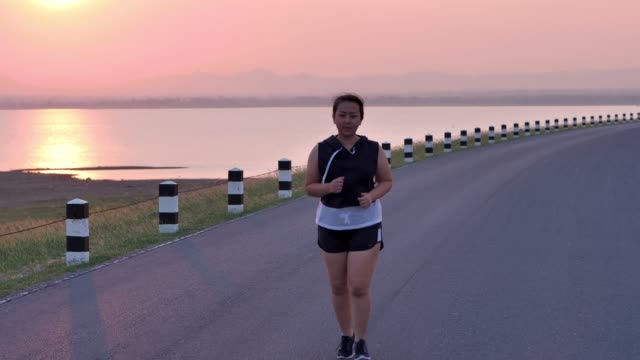 Overweight-Asian-women-jogging-in-the-street-in-the-early-morning-sunlight.-concept-of-losing-weight-with-exercise-for-health.-Slow-motion