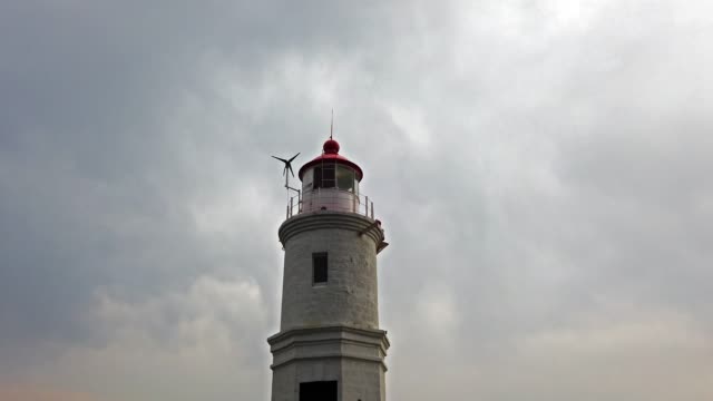 Landscape-with-a-white-lighthouse-against-a-cloudy-sky.