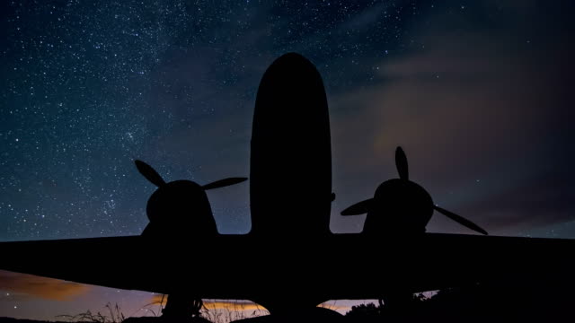 Stars-with-milky-way-moving-over-plane-silhouette-of-military-aircraft-in-starry-night-sky-Astronomy-Time-lapse