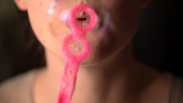closeup-macro-slow-motion-lips-blowing-bubbles-at-camera
