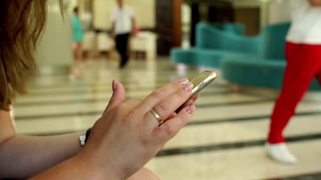 Close-up-of-a-girl-holding-a-phone-in-the-hotel,-and-child-looks-into-the-screen