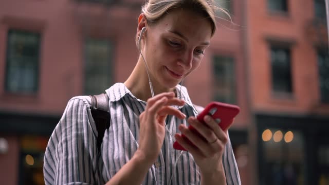 Zeitlupeneffekt-des-jungen-Hipster-Mädchens-in-Kopfhörern-hören-Lieblingsmusik-Songs-über-Smartphone-Anwendung