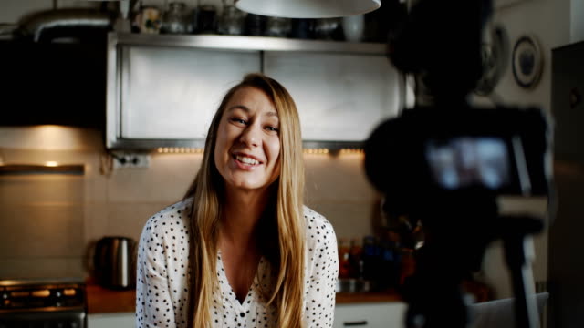 Happy-young-beautiful-food-blogger-woman-filming-new-vlog-video-with-professional-camera-in-the-kitchen-slow-motion.