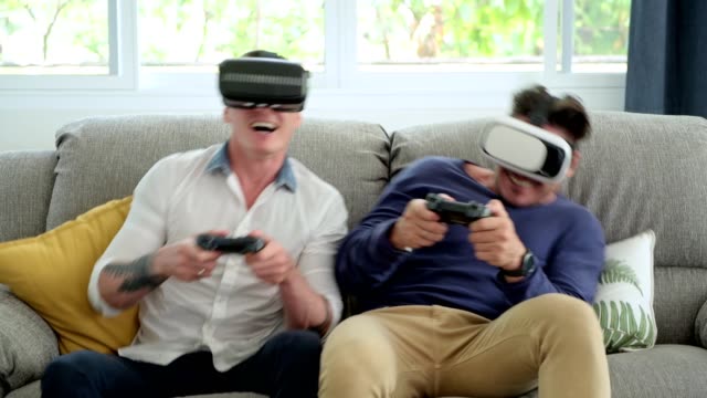 Schwules-Paar-entspannen-dan-auf-der-Couch-spielen-Virtual-Reality-Spiele.-Spannende-Stimmung.-Sehr-aufregende-Stimmung.