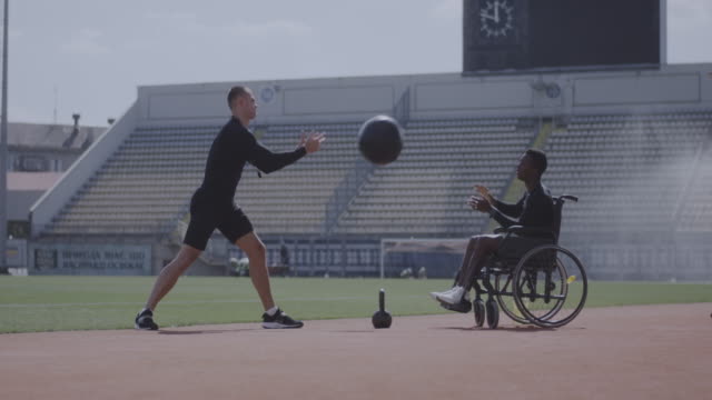 Wheelchaired-athlete-and-trainer-throwing-medicine-ball