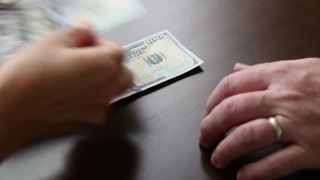 Mujer-contando-cien-dólares-bills-dinero-en-la-mesa-para-el-hombre